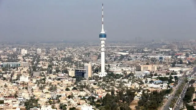 A tall communication tower amidst a sprawling urban cityscape.